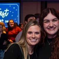 Two girls smile together with the Toast logo in the background.